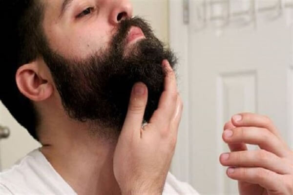 Мужчина втирает касторовое масло в бороду Касторовое масло для бороды